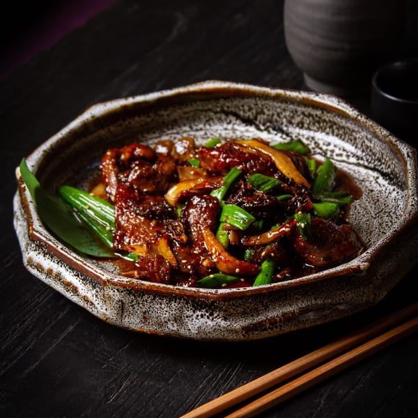 Tanuki River Landing's Asian-fusion dish with meat, mushrooms, and green onions in a dark sauce.