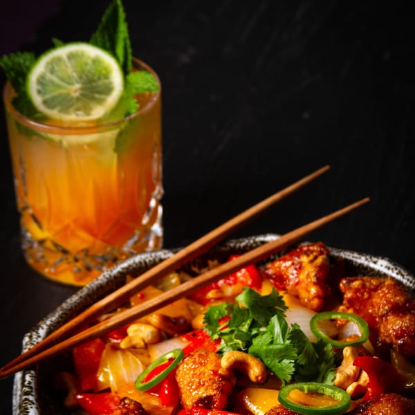 Tanuki River Landing's Asian-fusion dish with chicken, cashews, peppers, and a cocktail.