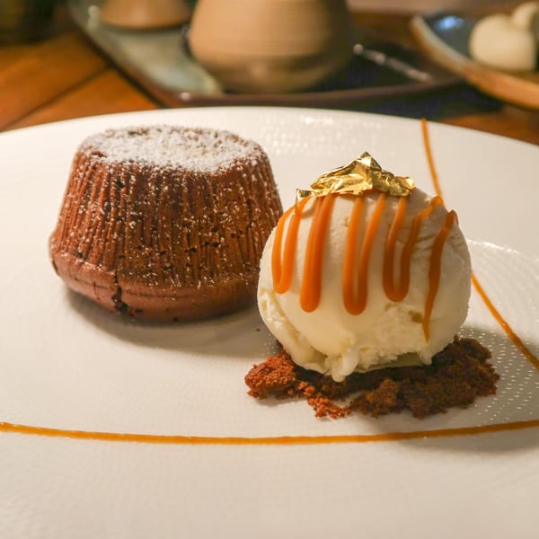 Chocolate lava cake with powdered sugar, vanilla ice cream with caramel drizzle and gold leaf.