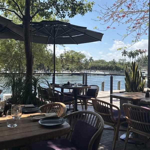 Outdoor dining area at Tanuki River Landing with tables, umbrellas, and a view of the river.