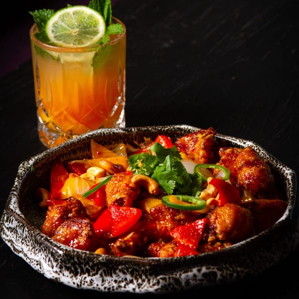 Tanuki River Landing's Asian-fusion dish with chicken, peppers, cashews, and a cocktail.