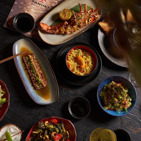 Overhead view of a Tanuki Miami River dinner spread with lobster, noodles, tuna, and cocktails.